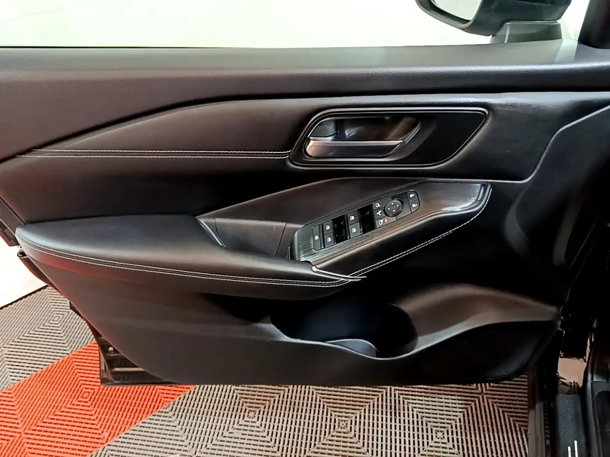 Vue intérieure côté gauche de la porte noire du Nissan Qashqai e-Power avec commandes des vitres et poignée alu.