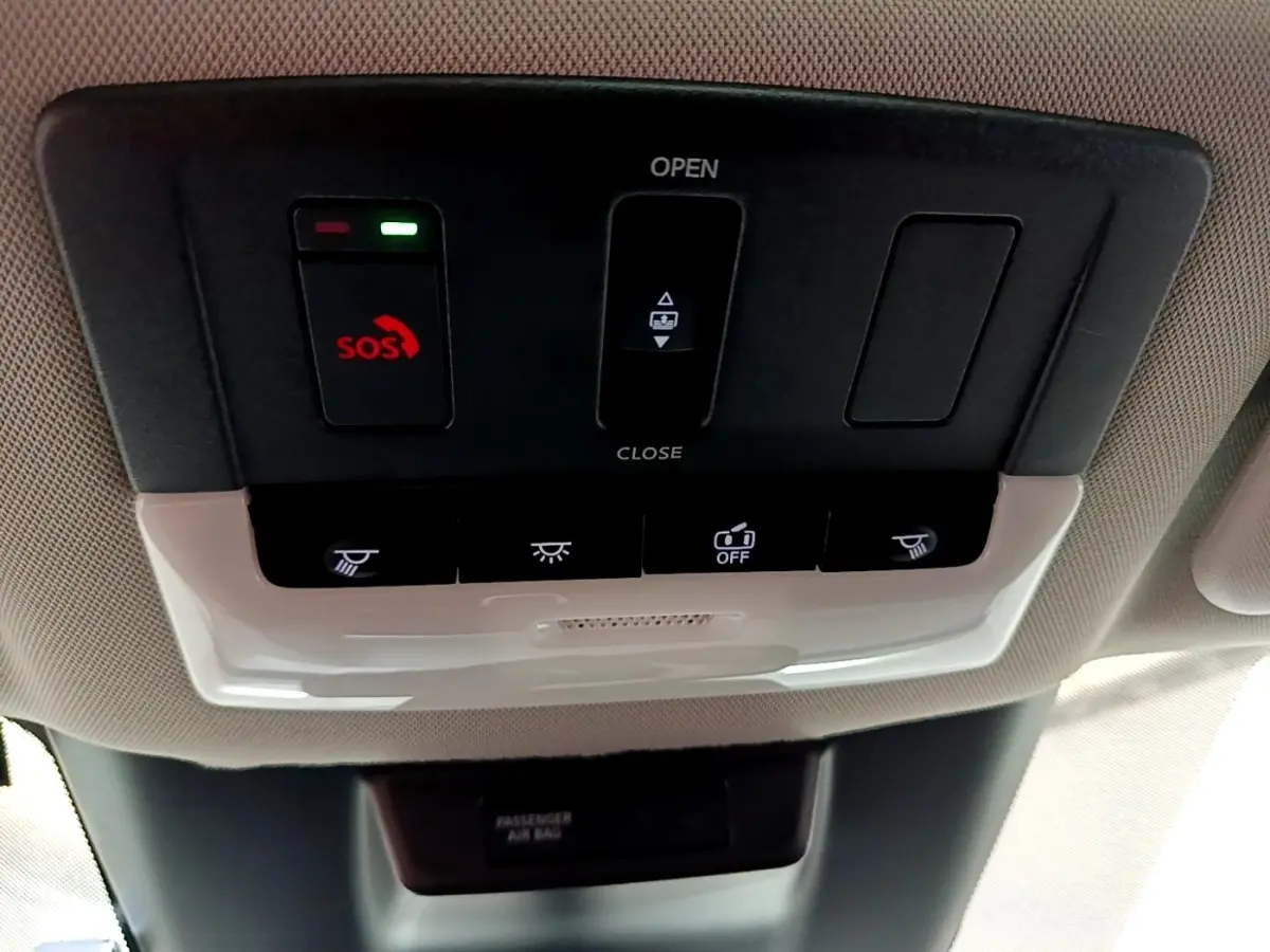 Vue en plongée sur le panneau de commandes de toit intérieur du Nissan Qashqai e-Power noir, avec bouton SOS rouge allumé.