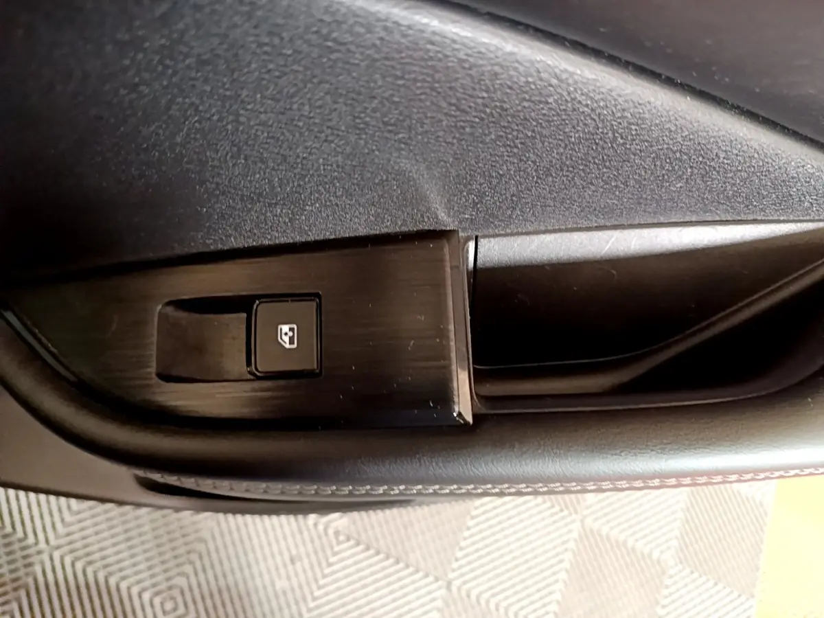 Gros plan sur le bouton de verrouillage de fenêtre côté conducteur du Nissan Qashqai e-Power noir 2023.