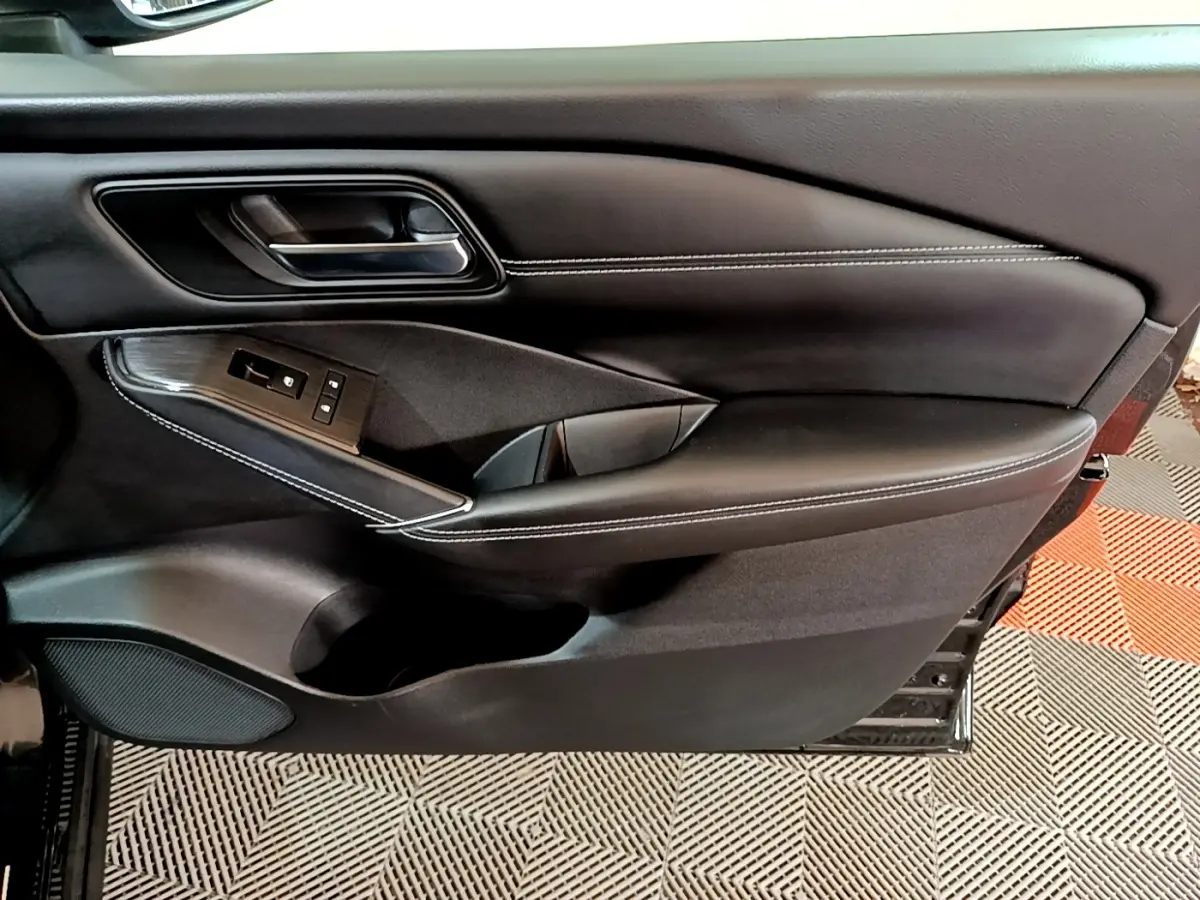 Gros plan sur la porte intérieure côté gauche du Nissan Qashqai e-Power 190 N-Connecta noire avec surpiqûres blanches et commandes électriques.