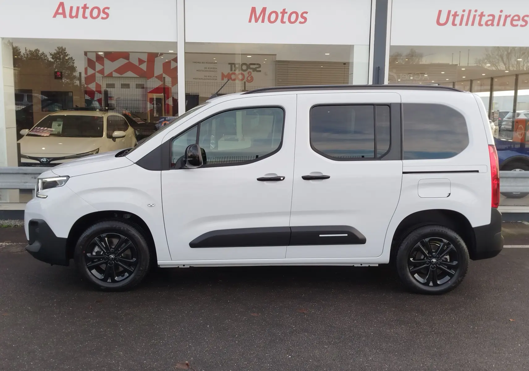 Profil droit d’un Citroën Berlingo Kaolin White 2025 avec jantes noires et protections latérales noires visibles.