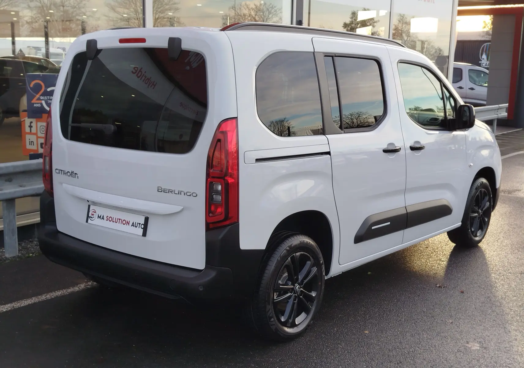 Vue 3/4 arrière droite du Citroën Berlingo Kaolin White avec vitres teintées et jantes noires.
