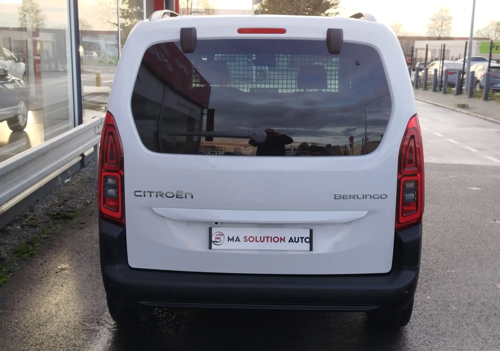 Vue arrière d'un Citroën Berlingo blanc Kaolin avec vitres teintées et feux arrière verticaux allumés.