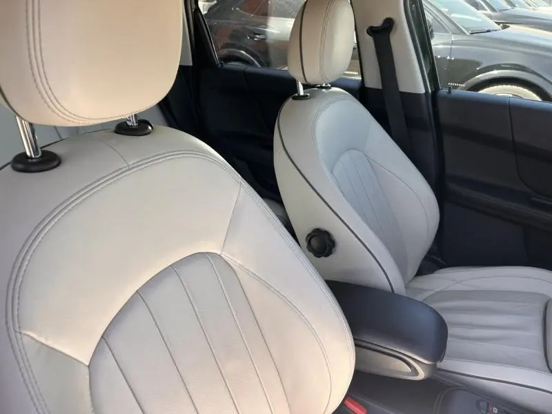 Gros plan sur les sièges avant en cuir clair de la MINI Countryman Cooper D 2018, avec accoudoir central noir.