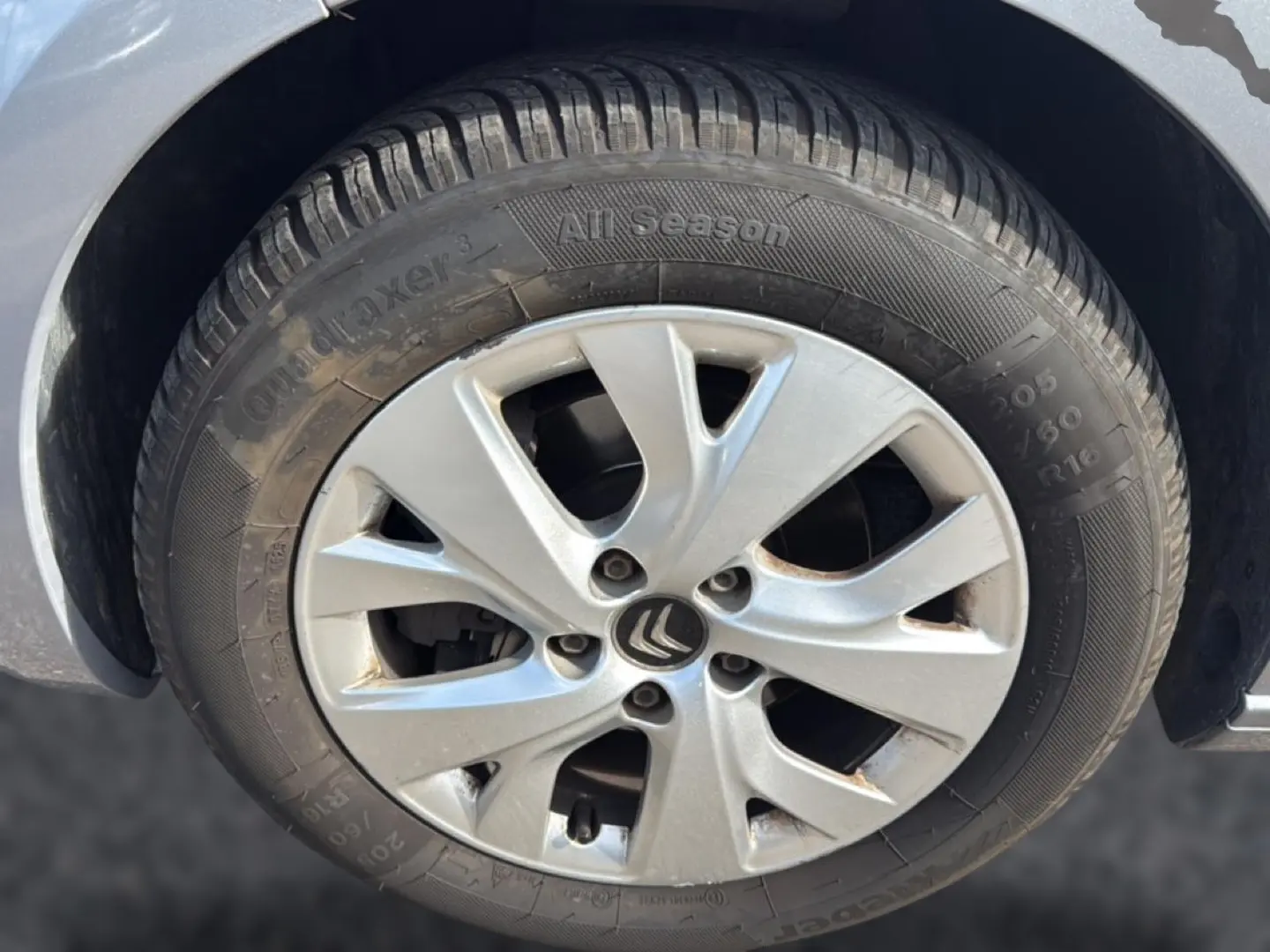 Gros plan sur la roue avant droite d’un Citroën Grand C4 Spacetourer gris alu avec jante alu à 5 branches doubles.