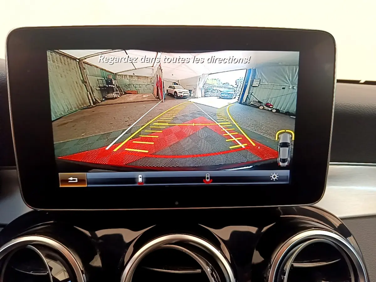 Écran central de la Mercedes Classe C Coupé noir 2018 montrant l’aide au stationnement avec vue arrière et guidage coloré.