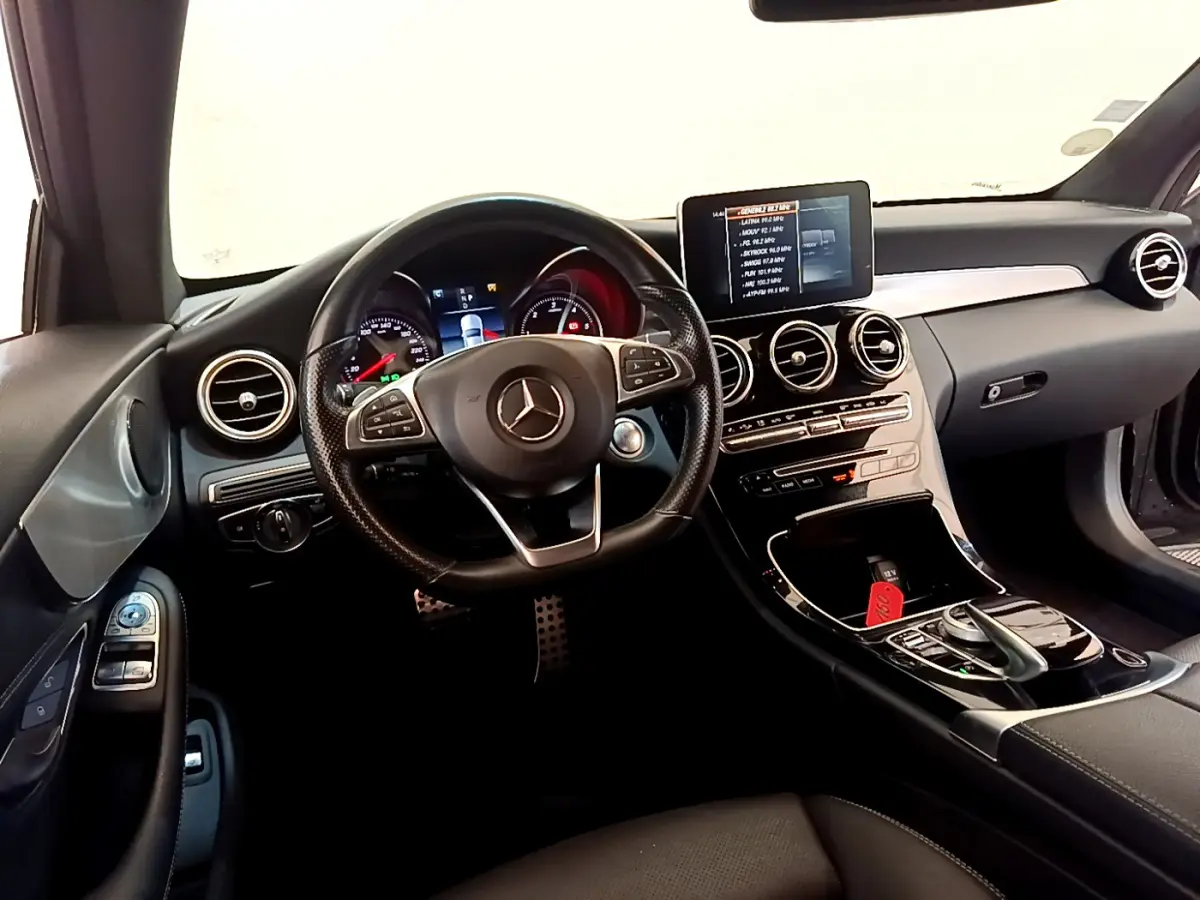 Vue intérieure avant de la Mercedes Classe C Coupé C 220 d Fascination 2018, tableau de bord noir avec écran central et volant multifonctions.