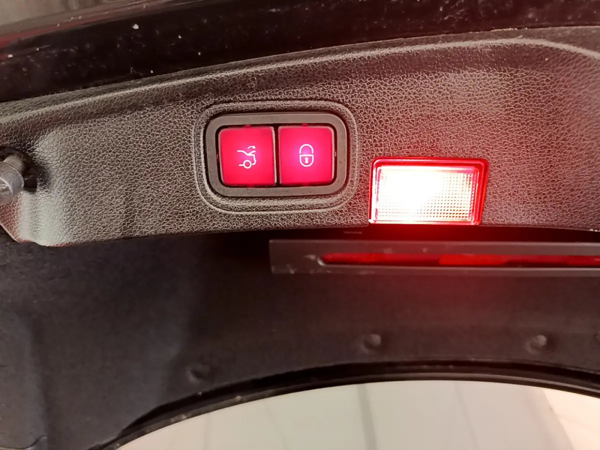 Gros plan sur les boutons d'ouverture et de verrouillage du coffre du Mercedes Classe C Coupé noir de 2018.
