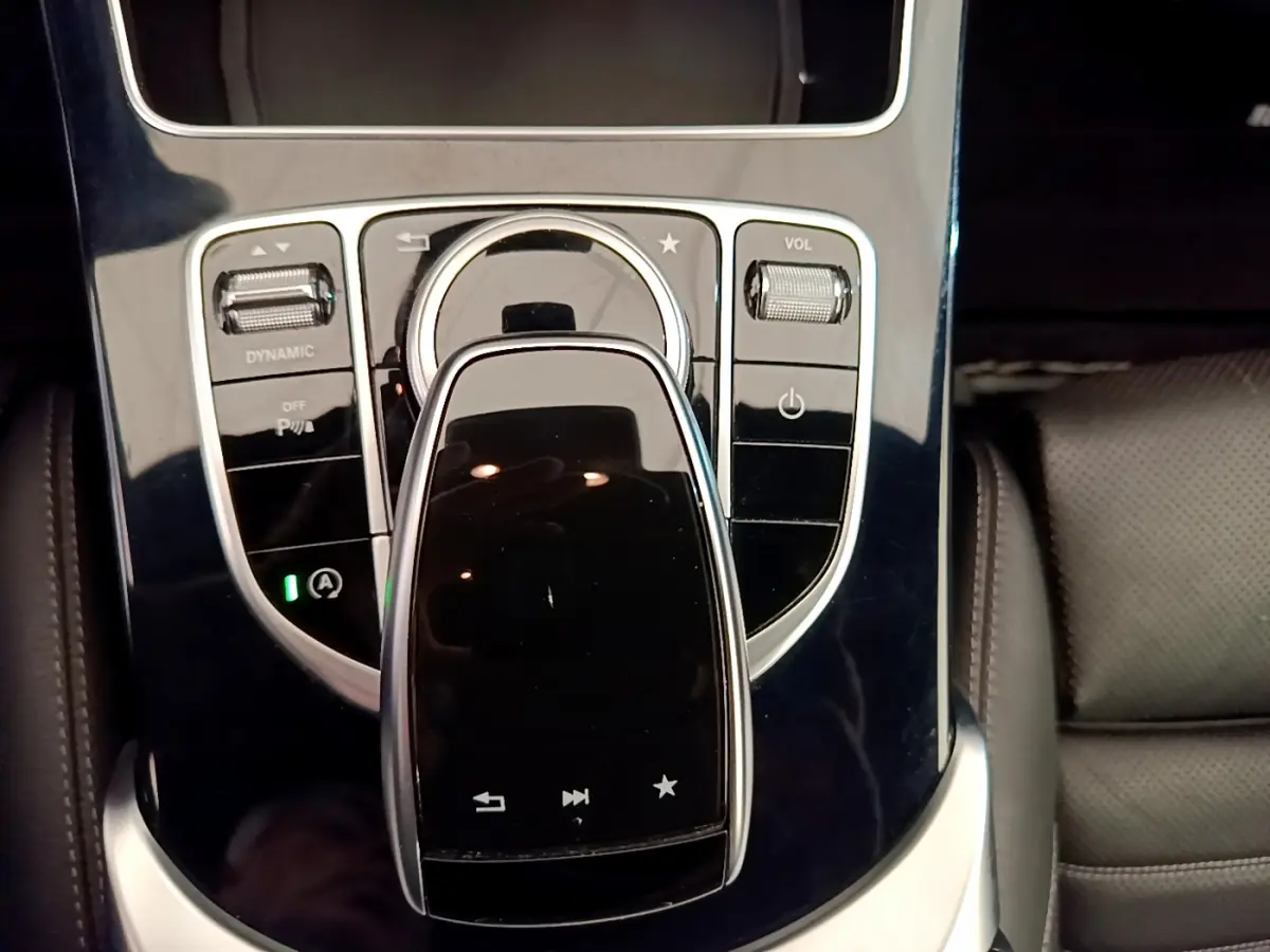 Gros plan sur la console centrale noire brillante de la Mercedes Classe C Coupé C 220 d Fascination 2018 avec commandes tactiles et molette.