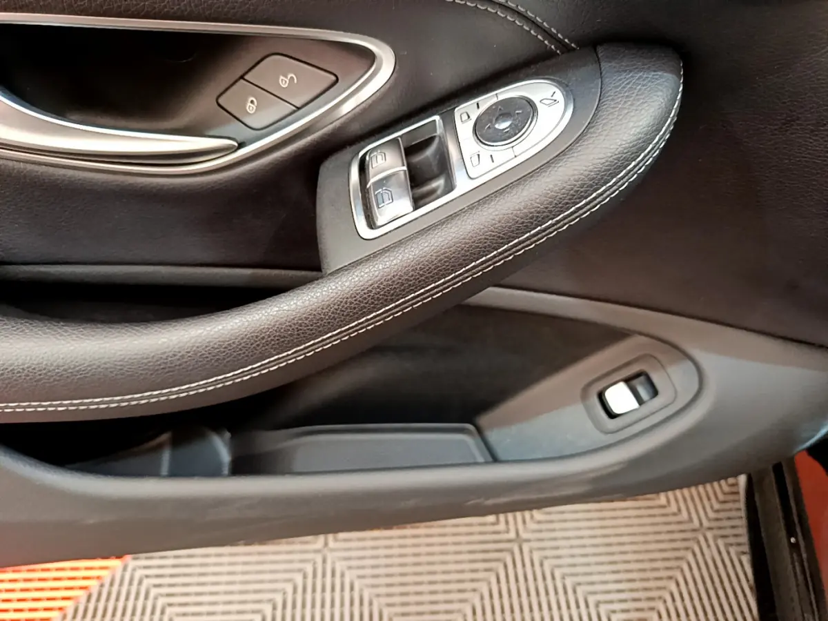 Gros plan sur la garniture intérieure noire de la porte côté conducteur avec commandes électriques des vitres et rétroviseurs.