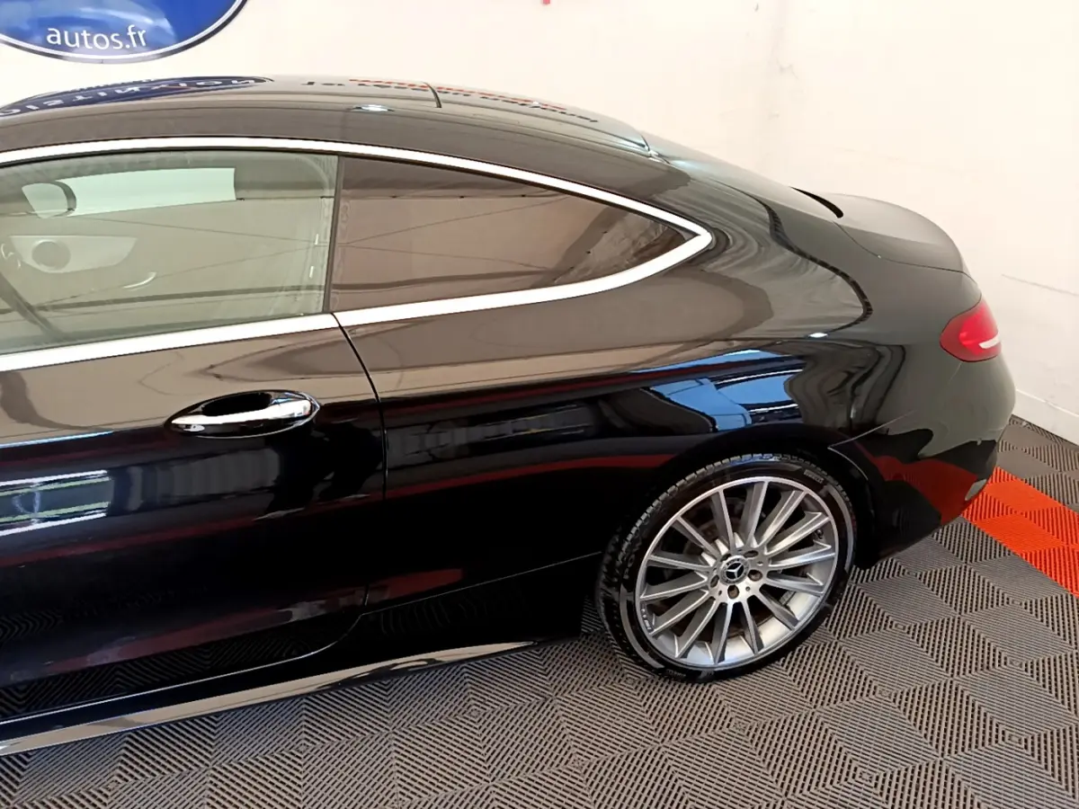 Vue latérale côté droit d'une Mercedes Classe C Coupé noire, mettant en valeur la jante alliage et la ligne fluide du toit.