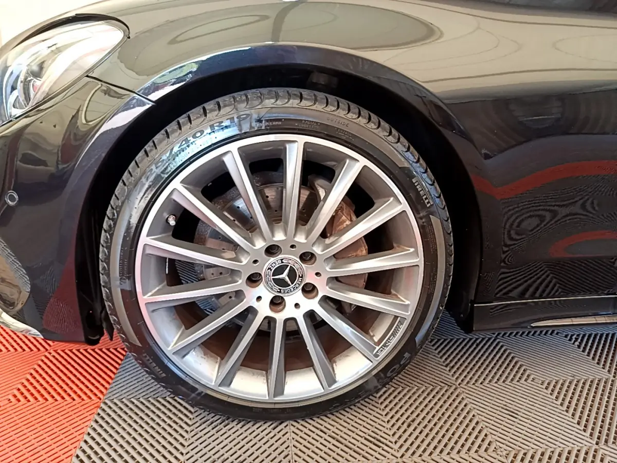 Gros plan sur la roue avant gauche d'une Mercedes Classe C Coupé noire, jante alliage multibranches et logo central visible.