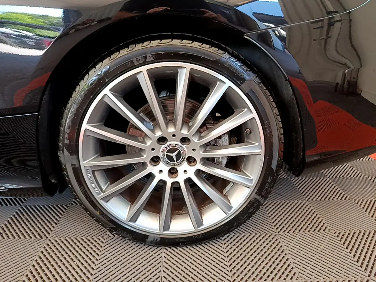 Gros plan sur la roue avant droite en alliage argenté d'une Mercedes Classe C Coupé noire, avec logo étoile central.