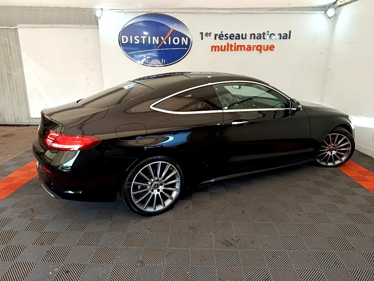 Mercedes Classe C Coupé C 220 d Fascination noir vue de profil côté gauche en intérieur showroom avec jantes alliage.