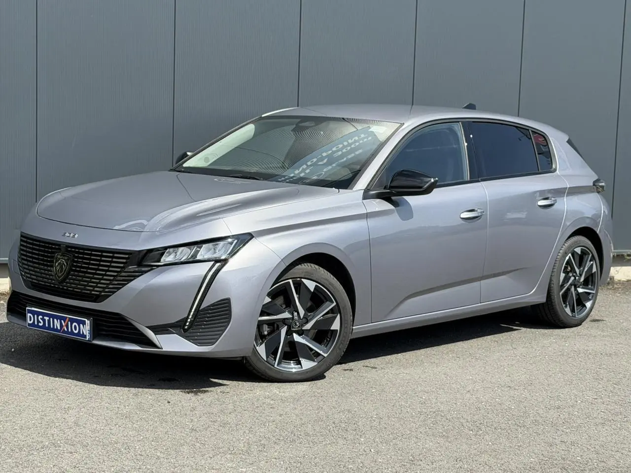 Peugeot 308 gris Artense vue 3/4 avant droit, jantes alliage 17'' et calandre noire distinctive.