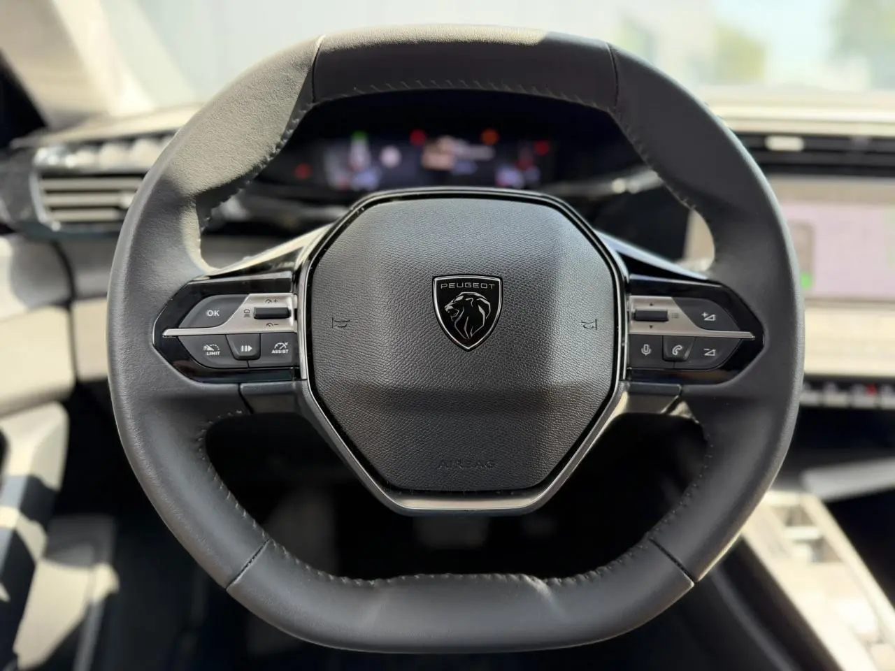 Vue rapprochée du volant cuir noir de la Peugeot 308 2025 avec commandes intégrées et logo central lion.
