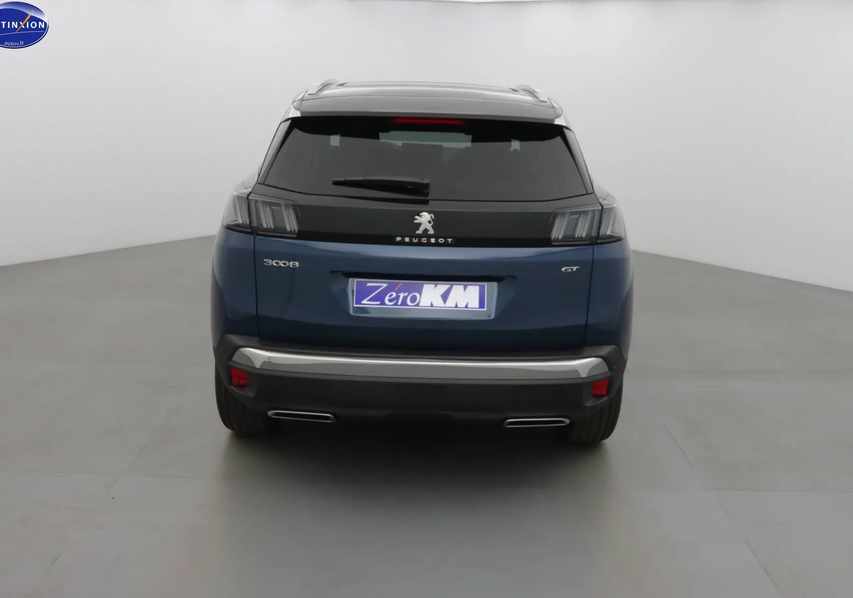 Vue arrière du Peugeot 3008 GT 2023 en bleu Celebes métal avec feux arrière sombres et double sortie d’échappement chromée.