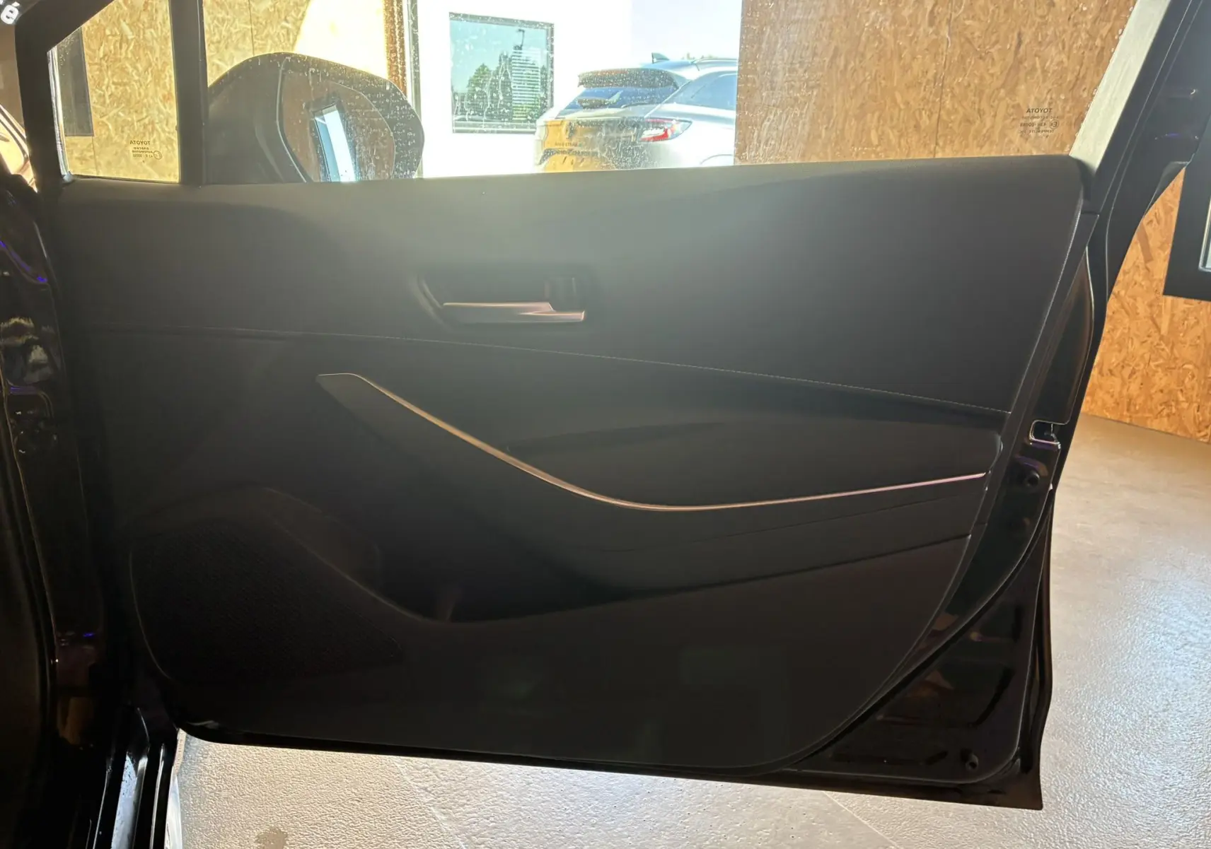 Vue intérieure de la porte côté gauche noire de la Toyota Corolla 1.8 122 Dynamic avec poignée et haut-parleur intégrés.