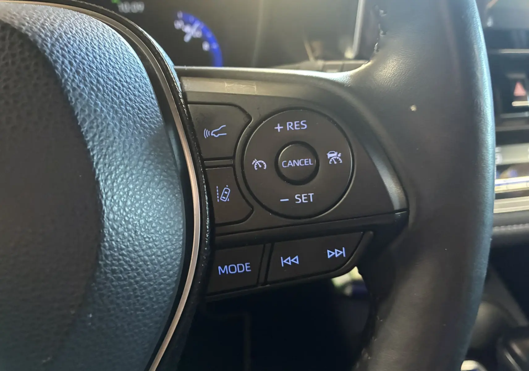 Gros plan sur le côté droit du volant noir de la Toyota Corolla 1.8 122 DYNAMIC 2020 avec commandes de régulateur et multimédia.