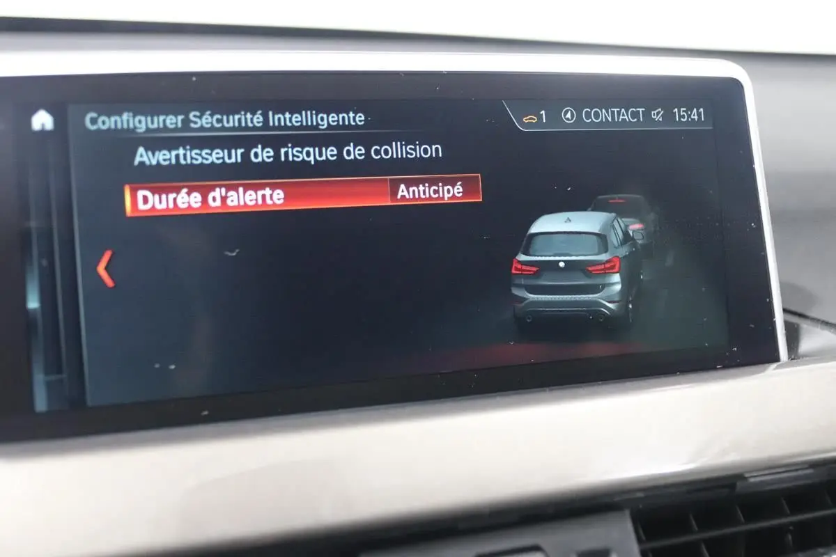 Écran de bord BMW X1 affichant l'alerte de risque de collision avec illustration du SUV gris vu de l'arrière.