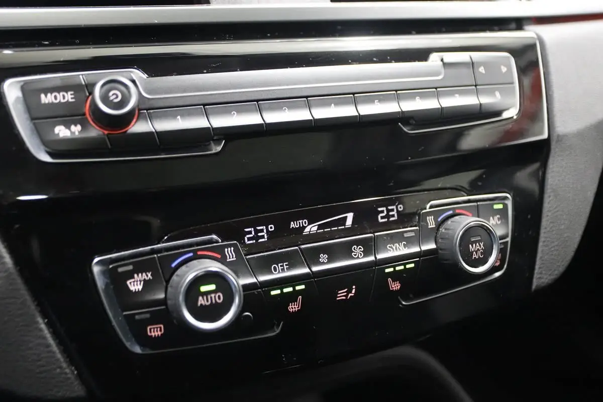 Gros plan sur la console centrale noire du BMW X1 2019, mettant en valeur les commandes de climatisation digitale.