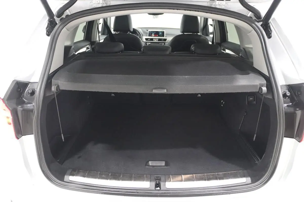 Coffre ouvert d’un BMW X1 argent métallisé vu de l’arrière, montrant l’espace de chargement et l’intérieur noir.