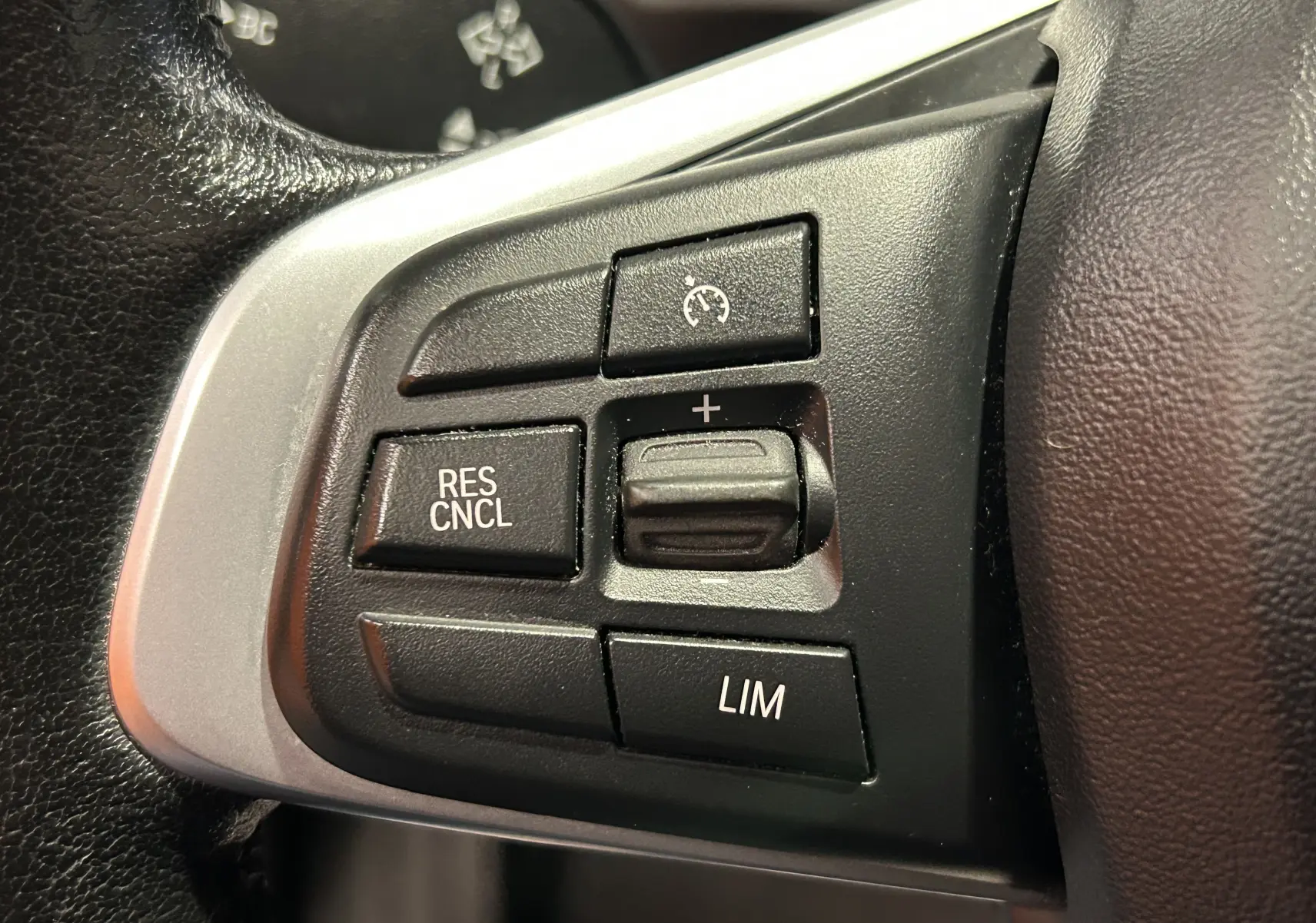 Gros plan sur les commandes de régulateur de vitesse au volant côté gauche d’un BMW X1 argenté de 2019.