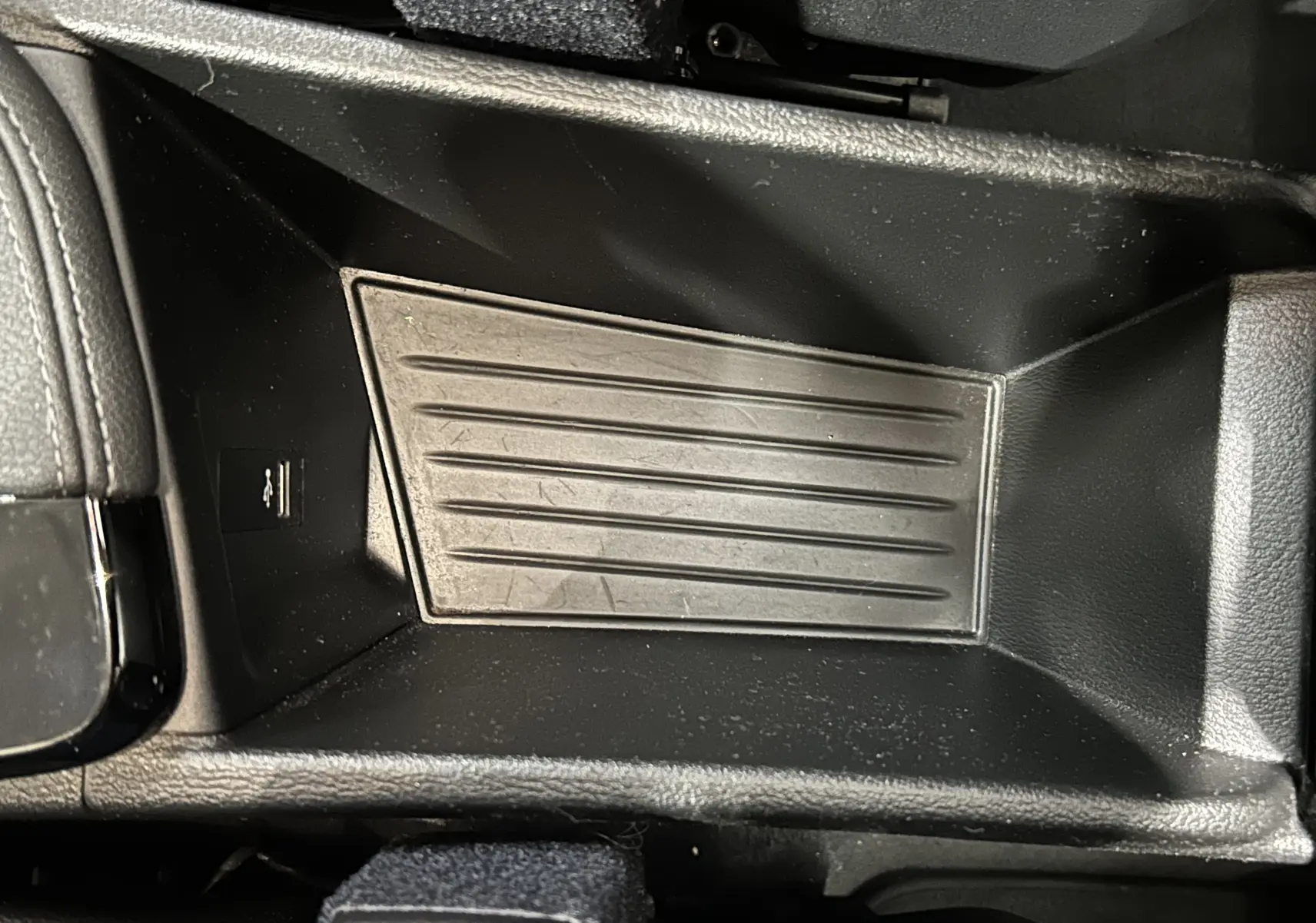 Gros plan sur le rangement central intérieur en plastique noir du BMW X1 sDrive 18D 2019, avec port USB visible.