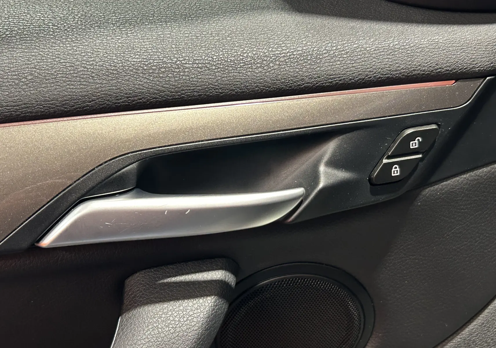 Détail de la poignée intérieure côté gauche en finition argentée avec boutons de verrouillage sur BMW X1 sDrive 18D 2019.
