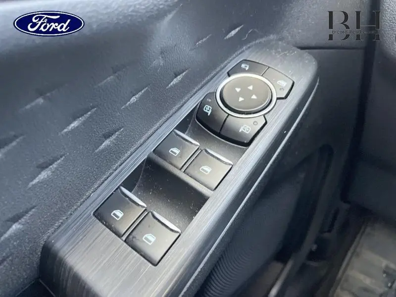 Gros plan sur les commandes de lève-vitres et rétroviseurs côté conducteur du Ford Kuga 2020 finition Titanium, intérieur noir.