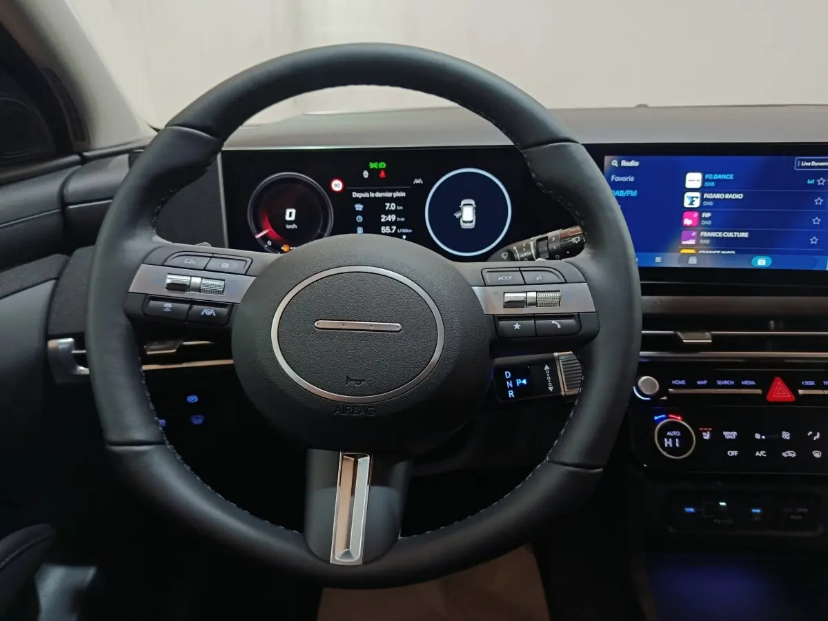 Vue intérieure centrée sur le volant cuir et les écrans digitaux du tableau de bord du Hyundai Tucson 2025.