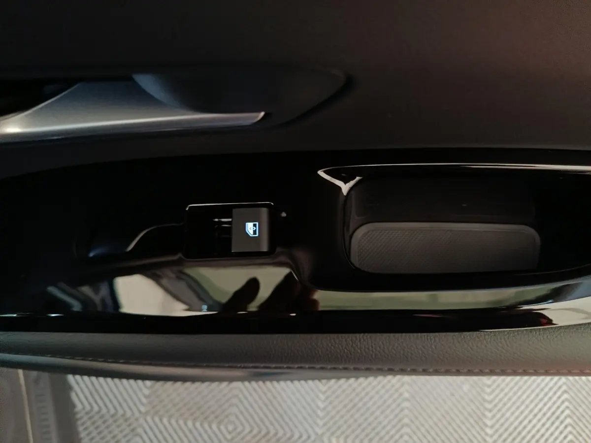 Gros plan sur la commande de lève-vitre avant gauche sur panneau de porte noir brillant du Hyundai Tucson gris clair.