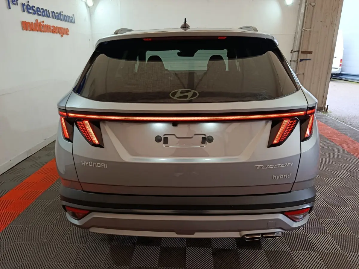 Vue arrière d'un Hyundai Tucson gris clair 2025 avec feux LED distinctifs et logo Hyundai visible sur le hayon.