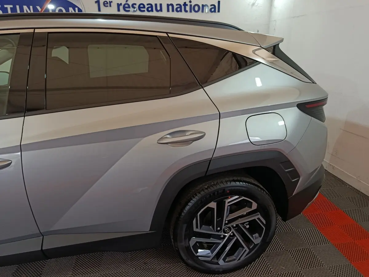 Vue latérale arrière droite du Hyundai Tucson gris clair 2025 avec jante alliage au design moderne et feux arrière LED.