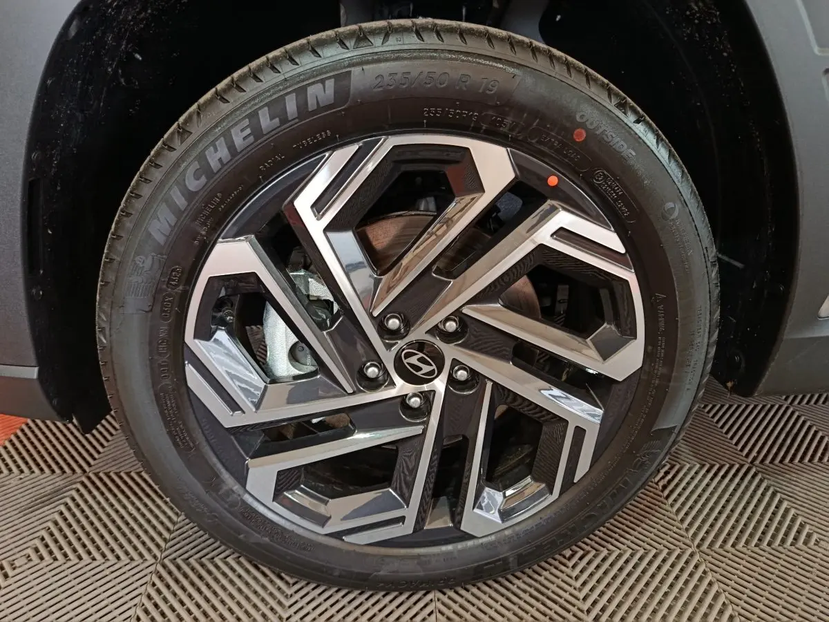 Gros plan sur la roue avant droite du Hyundai Tucson 2025 gris clair, mettant en valeur la jante alliage au design géométrique.