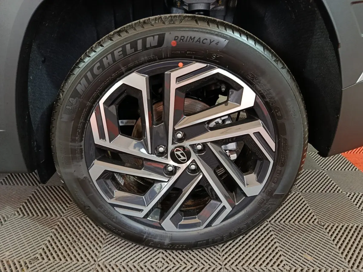 Gros plan sur la roue avant droite du Hyundai Tucson gris clair 2025 avec jante alliage au design géométrique.