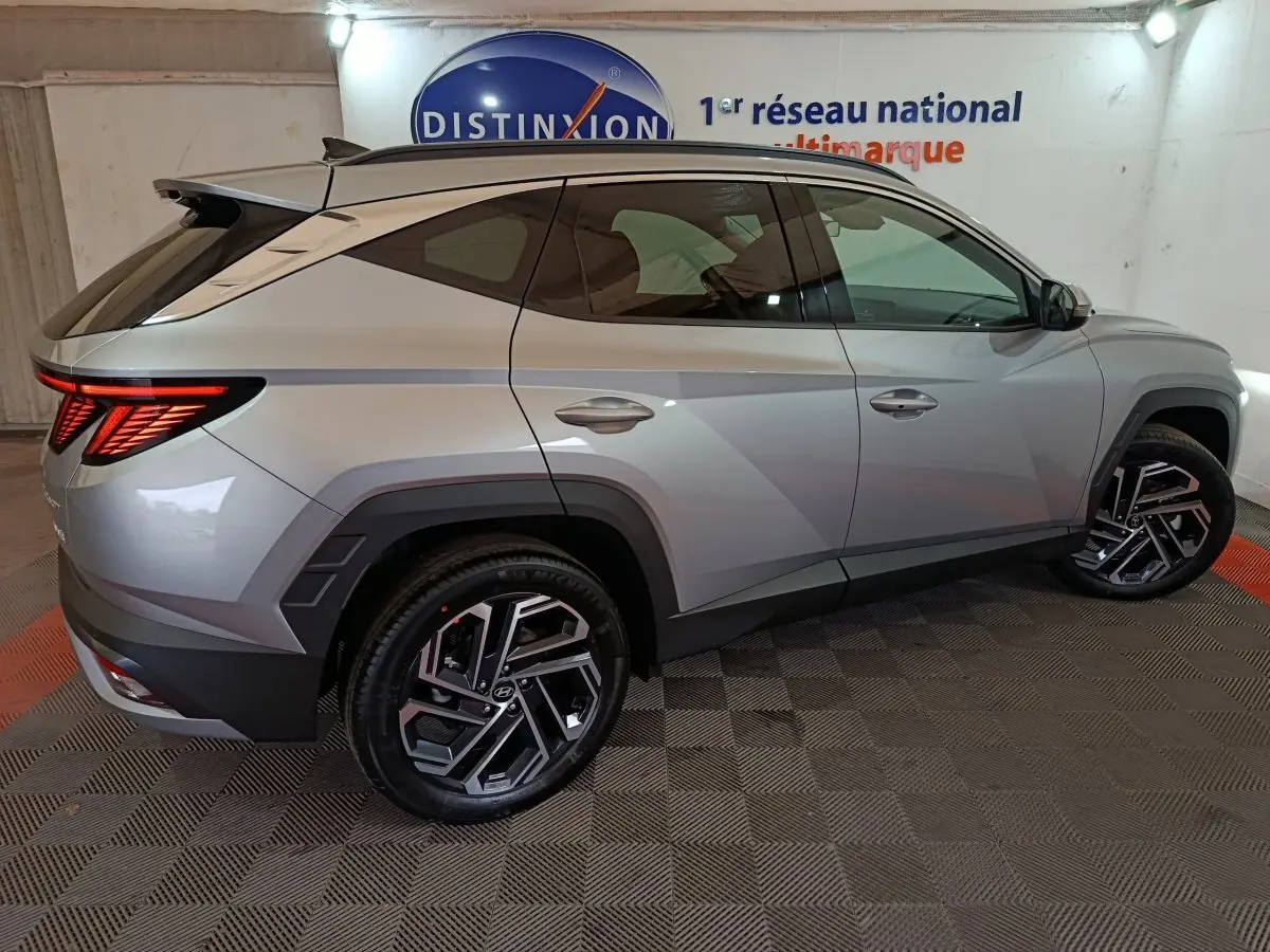 Vue latérale droite d'un Hyundai Tucson gris clair 2025 avec jantes noires et feux arrière LED allumés.