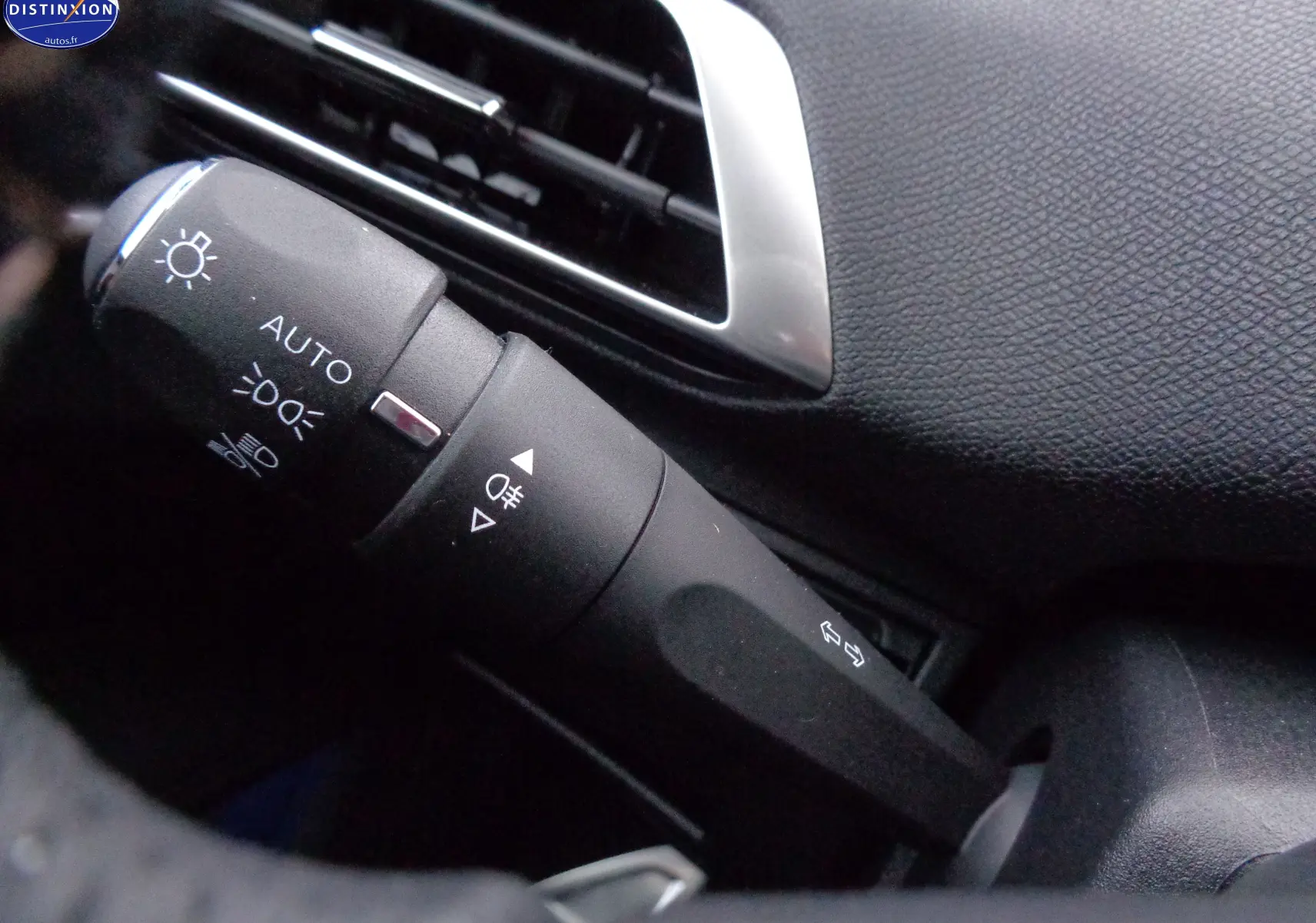 Gros plan sur la commande des feux et clignotants à gauche du volant dans l'habitacle noir du Peugeot 3008 2023.