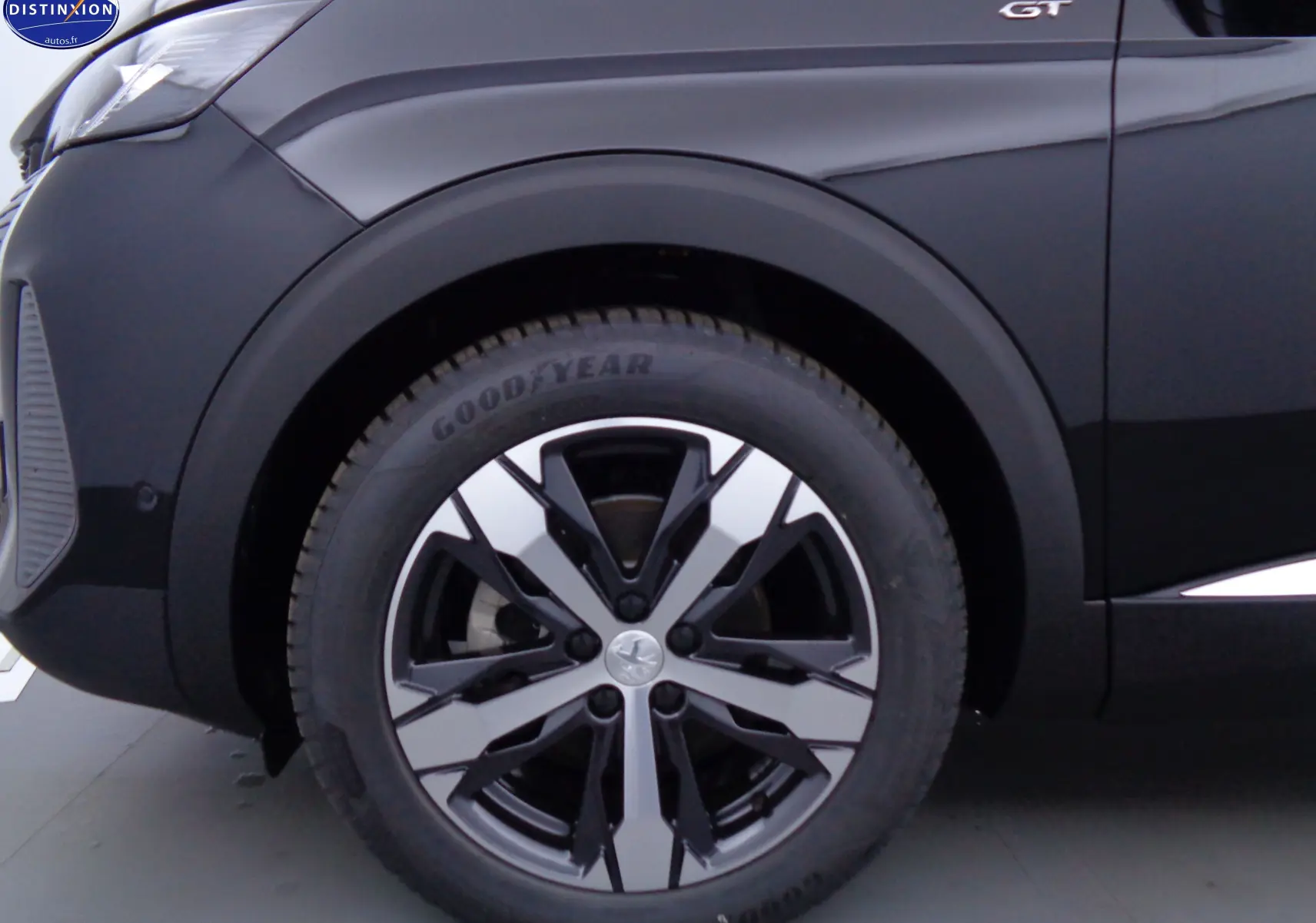 Gros plan sur la roue avant gauche noire perle métal d'un Peugeot 3008 GT 2023 avec jante bi-ton distinctive.