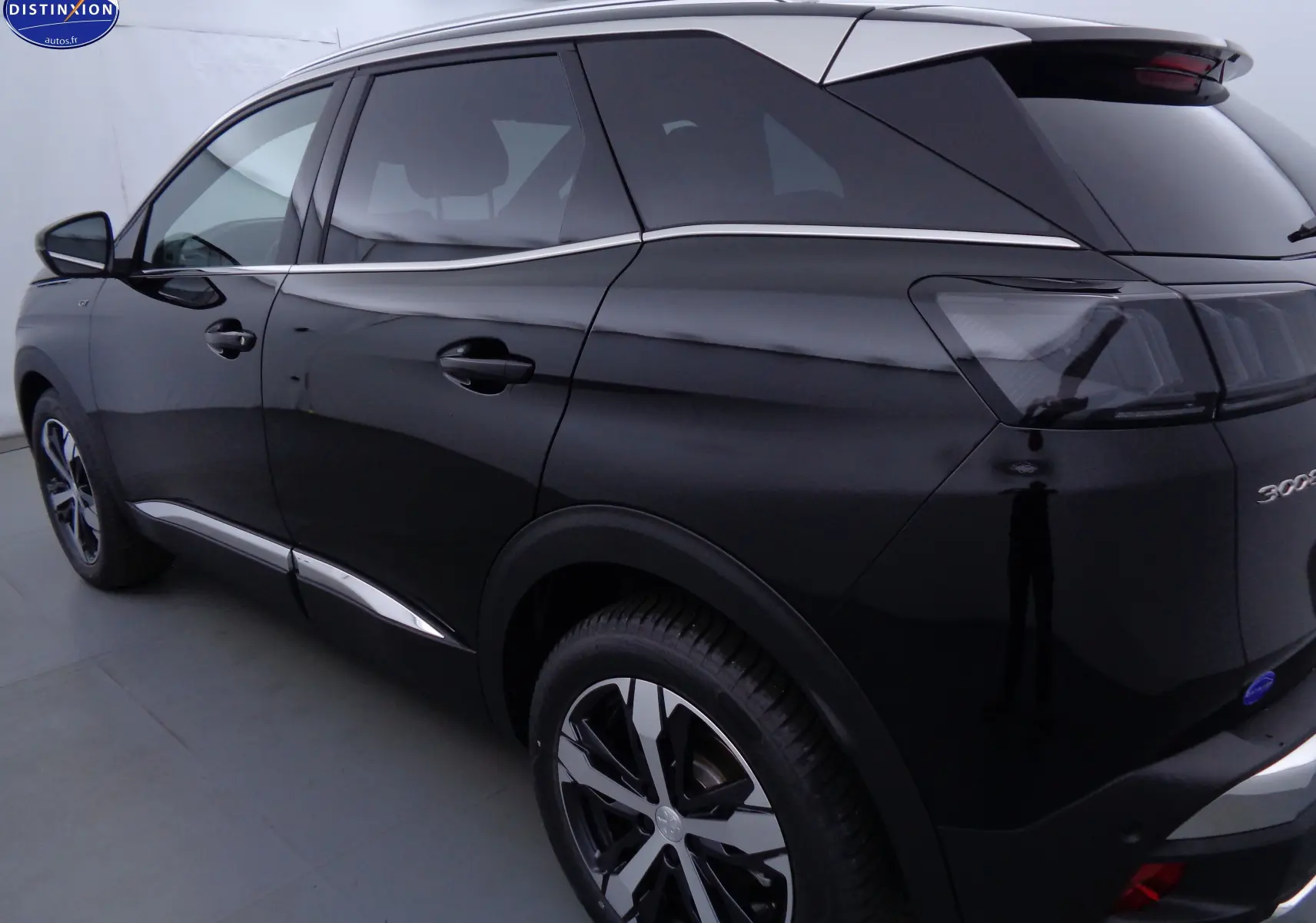 Vue 3/4 arrière droite du Peugeot 3008 GT noir perle métal avec jantes bi-ton et vitres teintées.