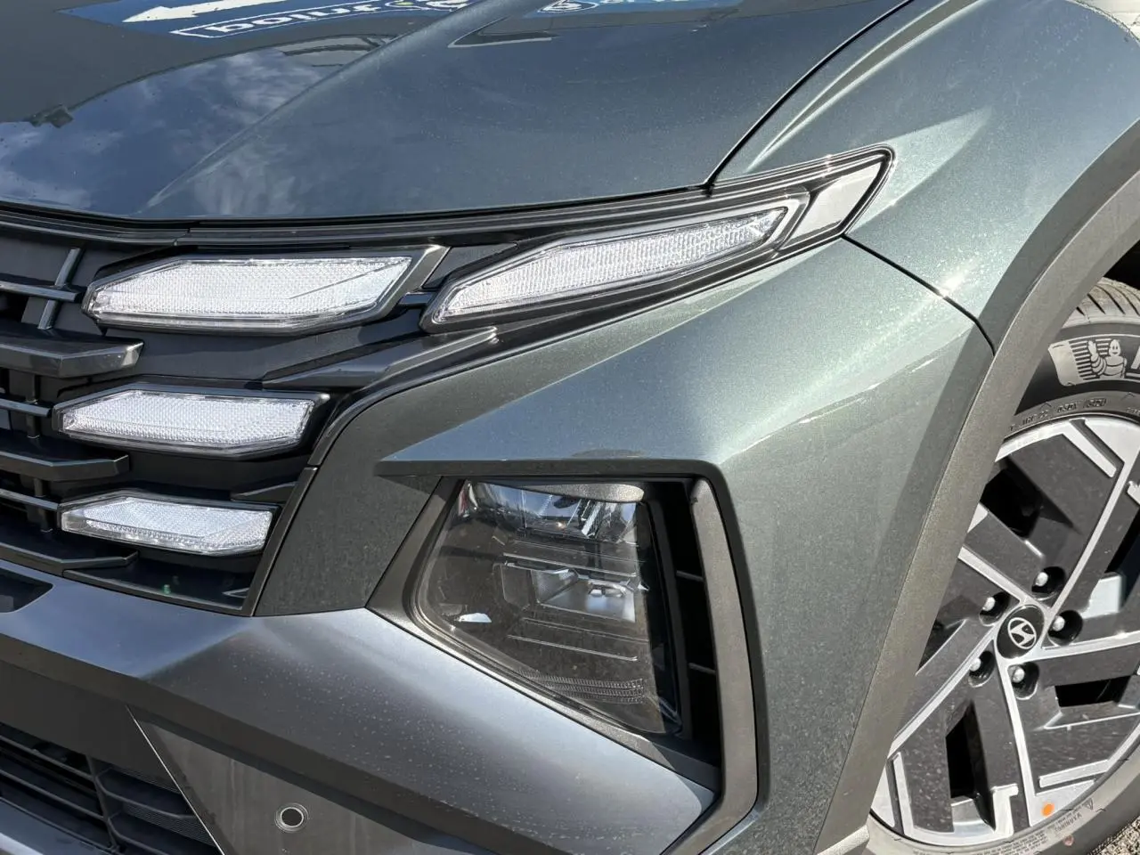 Gros plan sur l'avant droit du Hyundai Tucson Cypress Green 2025, mettant en valeur ses phares LED et jantes alliage.