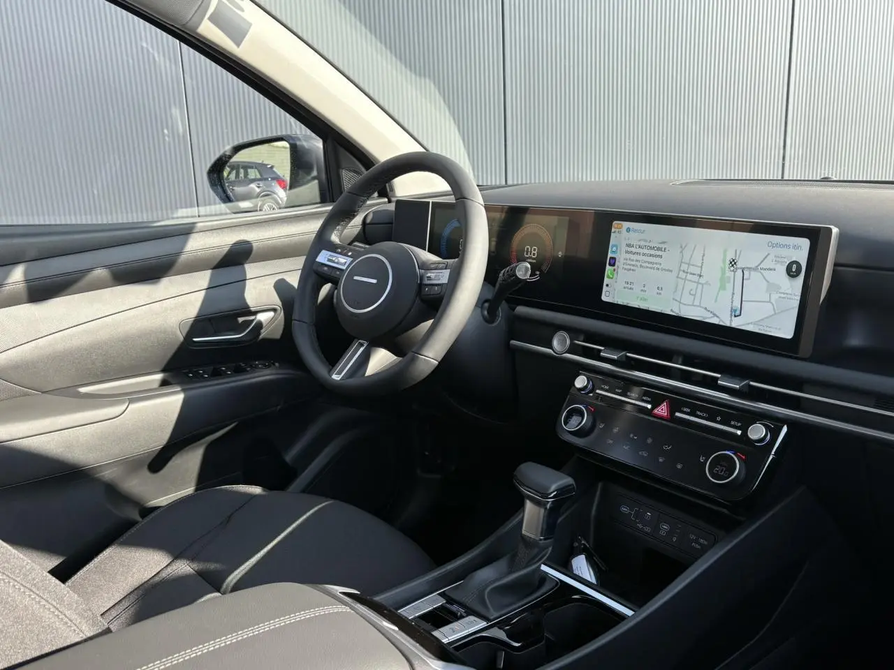 Intérieur avant gauche du Hyundai Tucson 2025 avec tableau de bord numérique et écran tactile large en navigation.