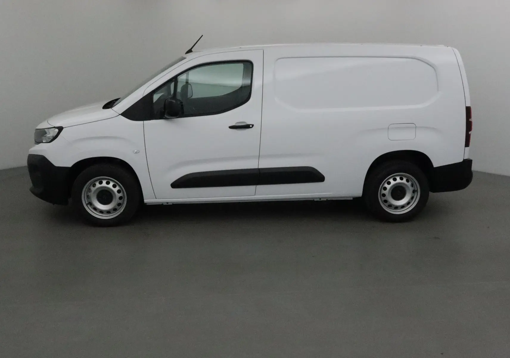 Profil côté gauche d'un utilitaire blanc Peugeot Partner XL 2025 avec protections noires et jantes acier simples.