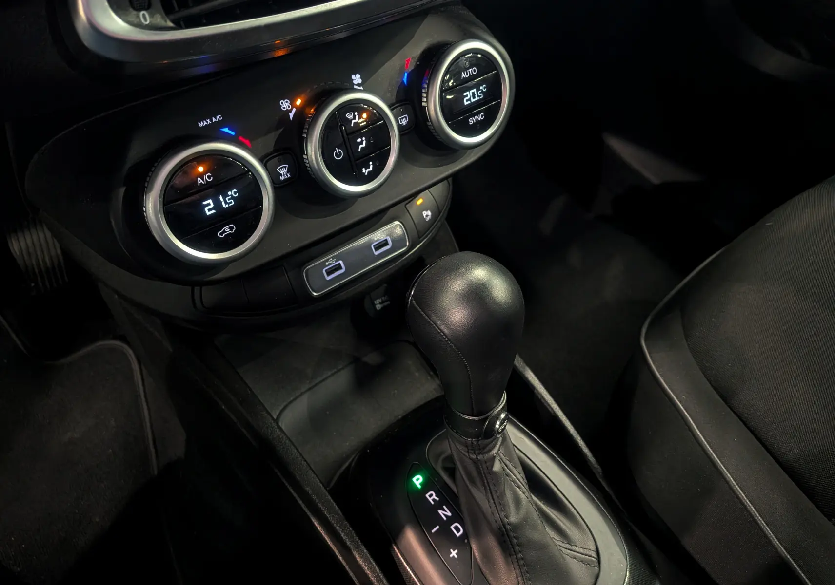 Gros plan sur la console centrale de la Fiat 500X 2024 avec levier de boîte auto et commandes de climatisation digitales.