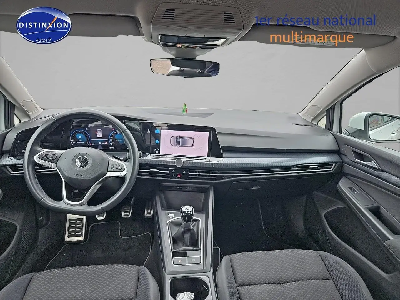 Intérieur avant de la Volkswagen Golf blanche 2021, vue de face sur le tableau de bord et le volant cuir multifonction.
