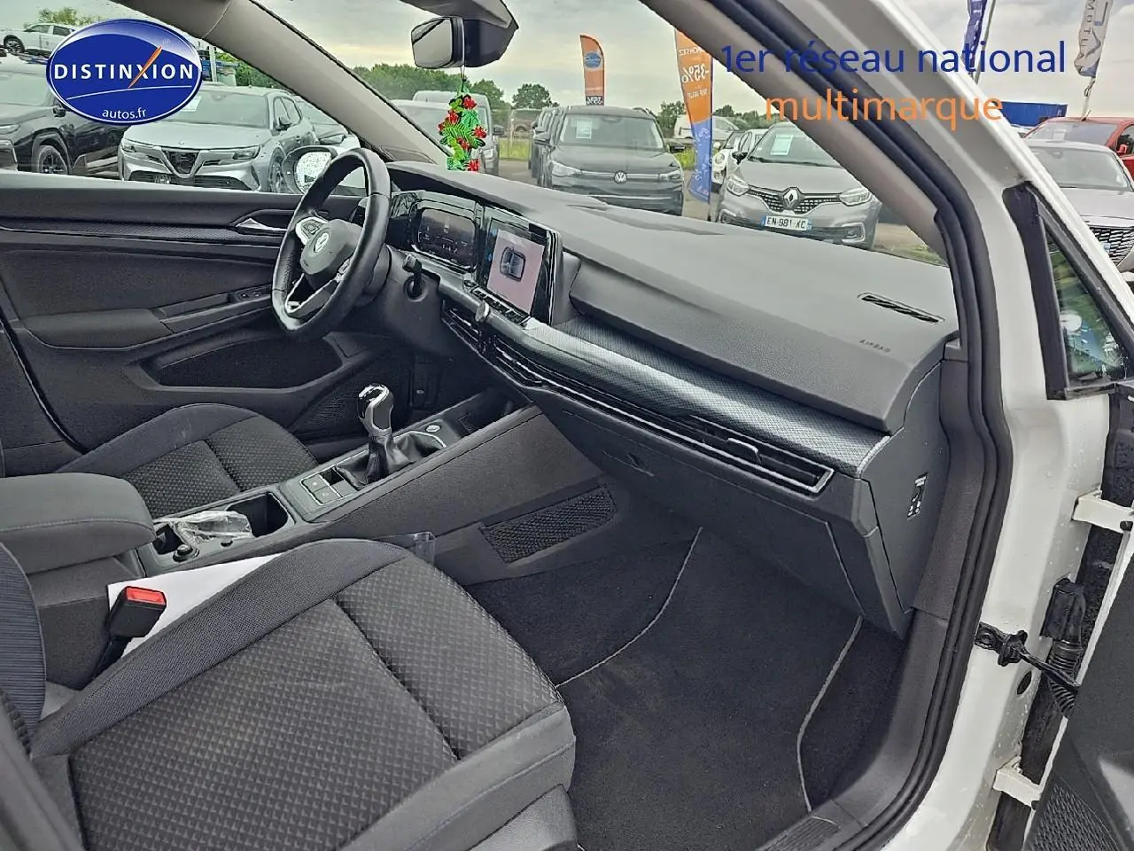 Vue intérieure côté passager d'une Volkswagen Golf blanche 2021 avec tableau de bord moderne et boîte manuelle.