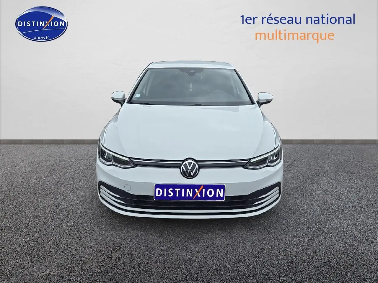 Vue frontale d'une Volkswagen Golf blanche 2021 avec phares LED et calandre épurée sur fond neutre.
