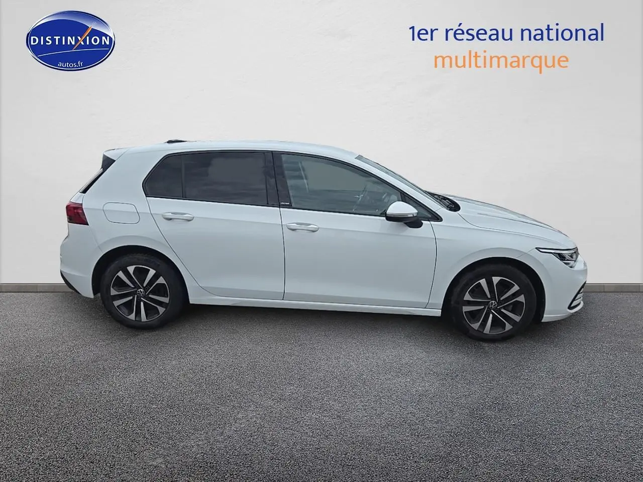 Profil droit d'une Volkswagen Golf blanche 2021 avec jantes alliage et vitres teintées sur fond neutre.