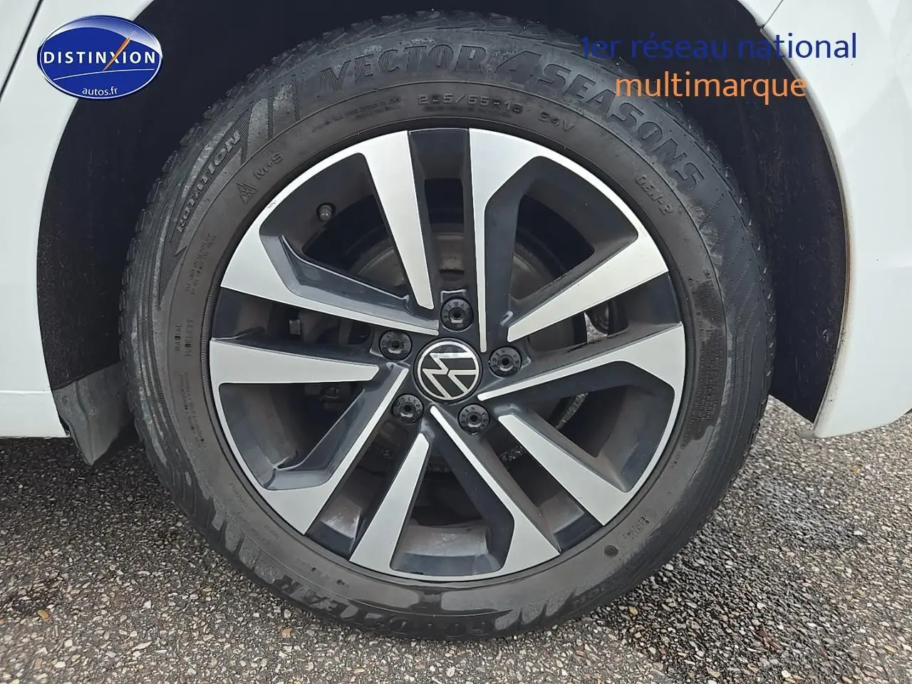 Gros plan sur la roue avant droite d'une Volkswagen Golf blanche avec jante alliage bicolore.