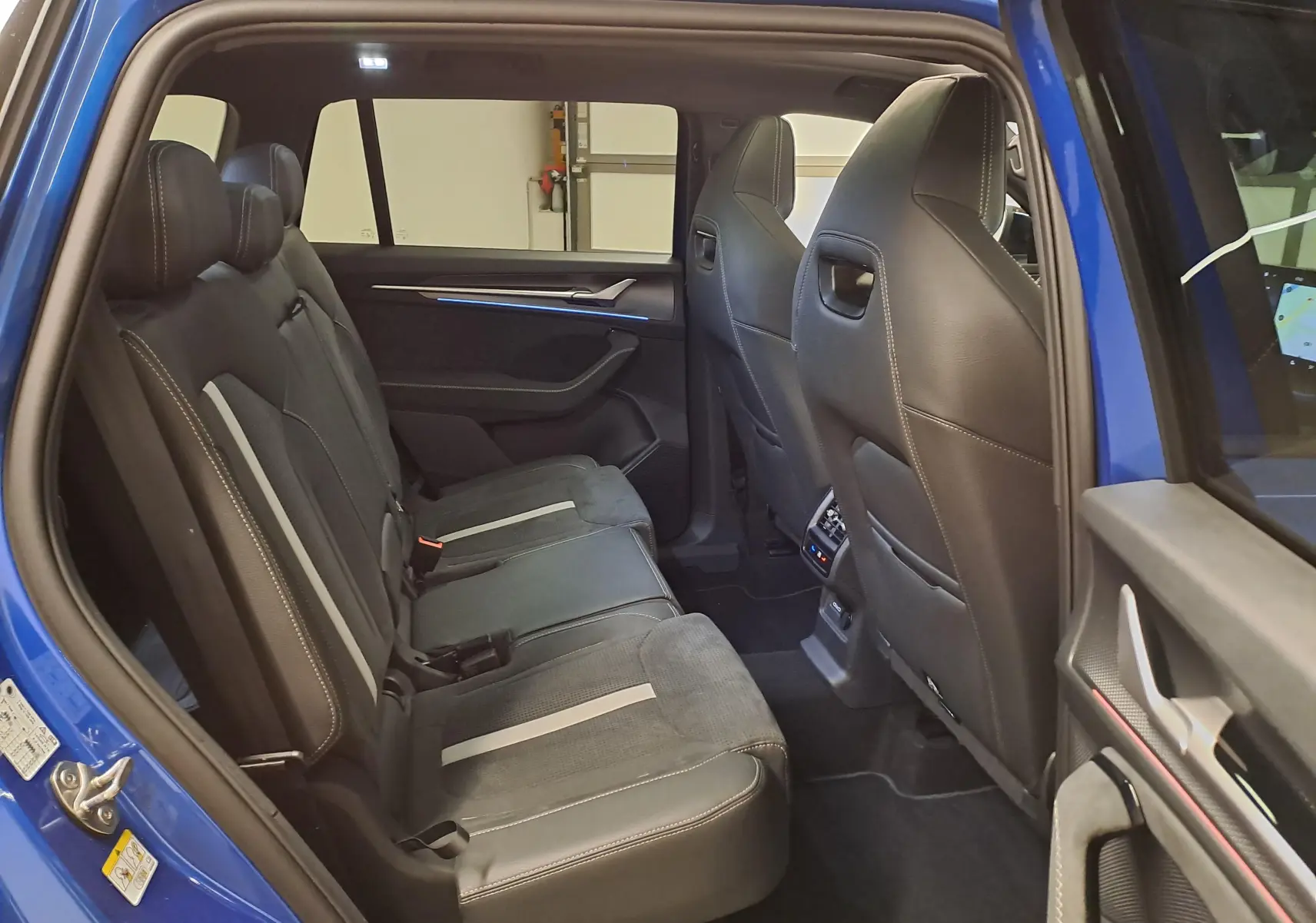 Vue intérieure côté gauche des sièges arrière en cuir noir avec surpiqûres blanches du Skoda Kodiaq Bleu RS 2025.